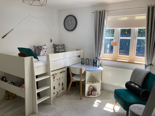 Cabin bed with Harry Potter themed drawers and desk underneath, clock and magic wand on the wall