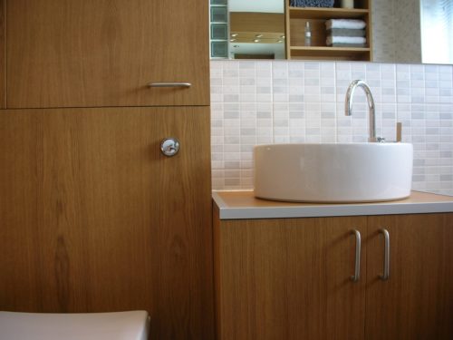 Oak vanity unit with round white wash basin and tap and concealed cistern toilet