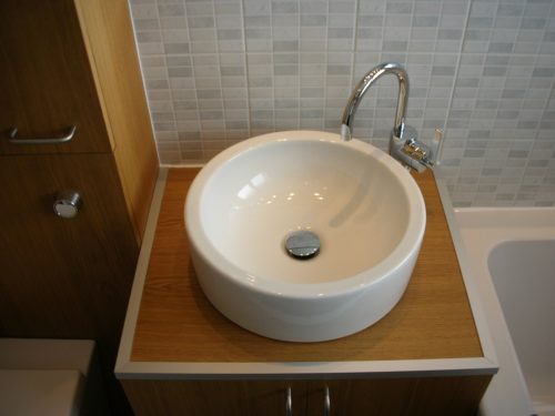 Oak bathroom vanity unit with modern round basin and tap