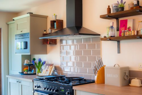 Black range cooker and hood with sage green metro brick tiles