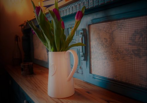 Blue unit up close with purple tulips in a white jug