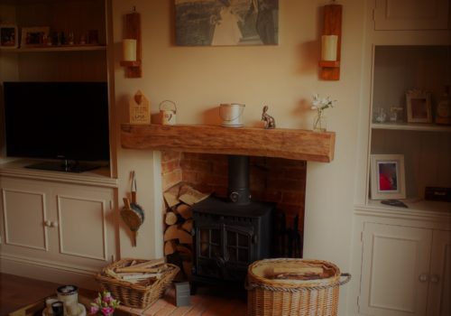 Lounge with fireplace, mantle piece and log burner, alcove shelving and units either side