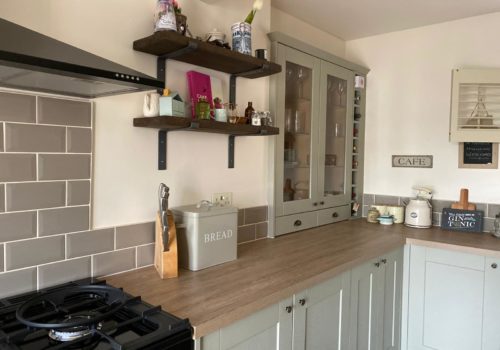 Kitchen view with green units and glass cabinets