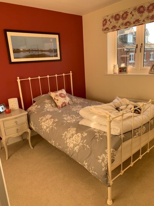 Guest Bedroom with iron bed, red feature wall